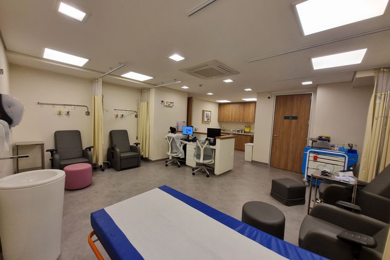 Sala de atendimento com poltronas, maca e estação de enfermagem